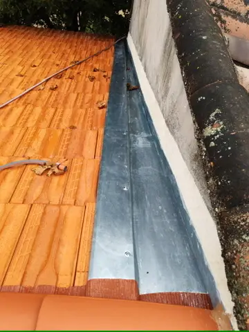 Détail d'une gouttière zinc posée en pied de toiture avec descente d'eau pluviale
