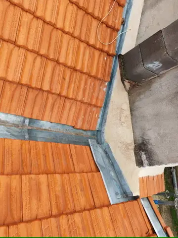 Détail d'un habillage zinc en angle de toiture contre un mur